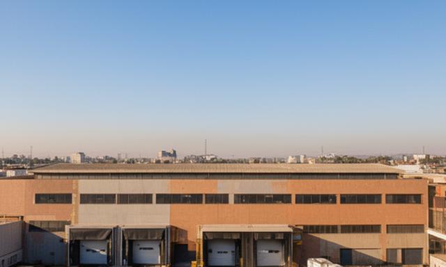 Exterior de una planta industrial en Buenos Aires con acceso de carga y cielo despejado
